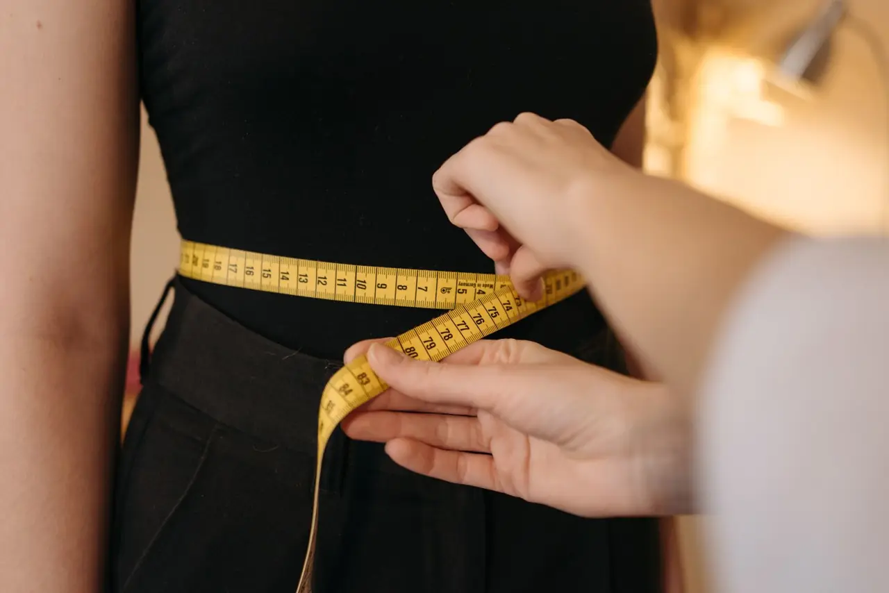 Tailor measuring a dress at the waist